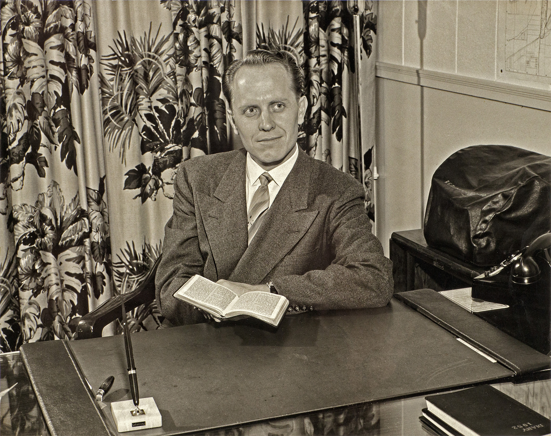 Carl Spain at his desk with a Bible